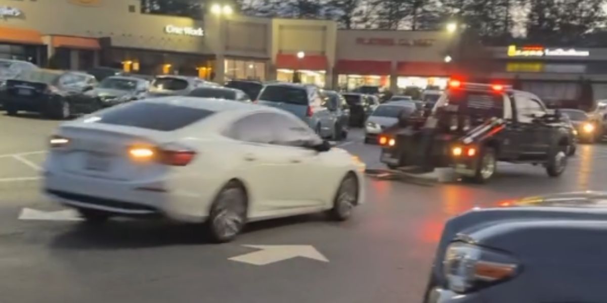 Kvinna flyr från en bärgningsbil på en parkeringsplats i ett ovanligt videoklipp